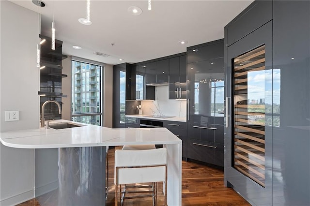 kitchen with dark cabinets, black electric cooktop, oven, decorative backsplash, and under cabinet range hood