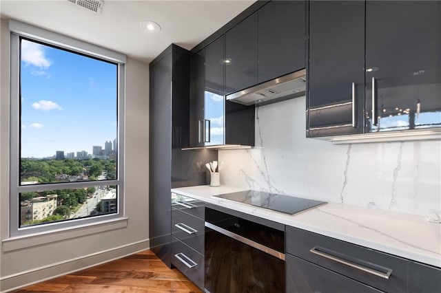 kitchen with a sink, dark wood-type flooring, modern cabinets, recessed lighting, and light stone countertops