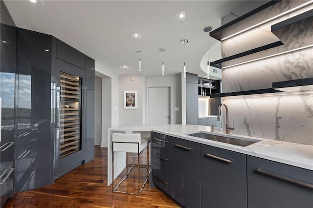 kitchen featuring oven, a sink, modern cabinets, and dark cabinets