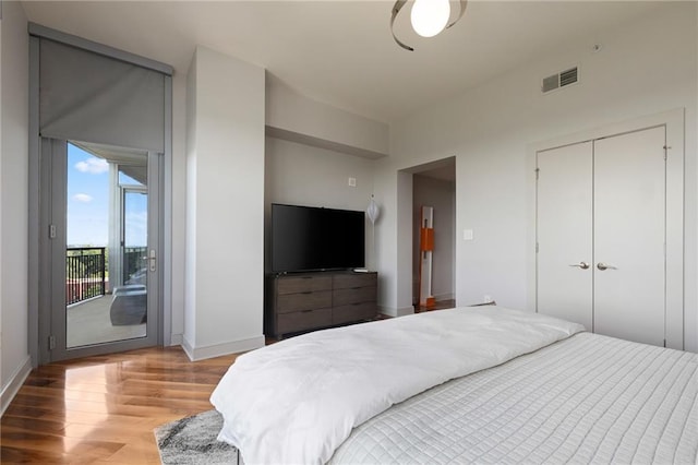 bedroom with multiple windows, wood finished floors, baseboards, and access to outside
