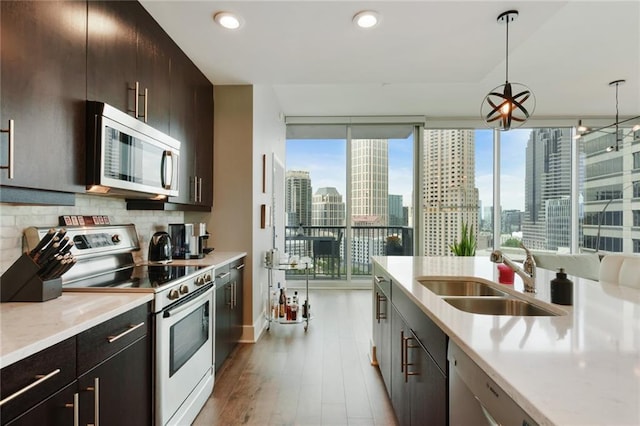 kitchen featuring decorative light fixtures, white range, plenty of natural light, and sink