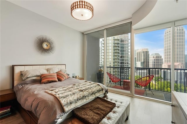 bedroom with access to outside, expansive windows, and wood-type flooring