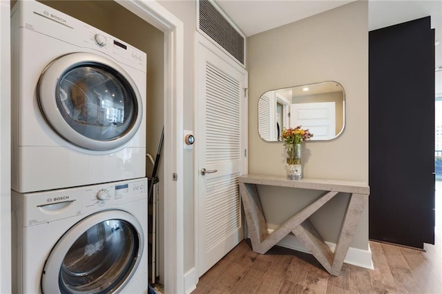 laundry room featuring stacked washer / drying machine and light wood-type flooring