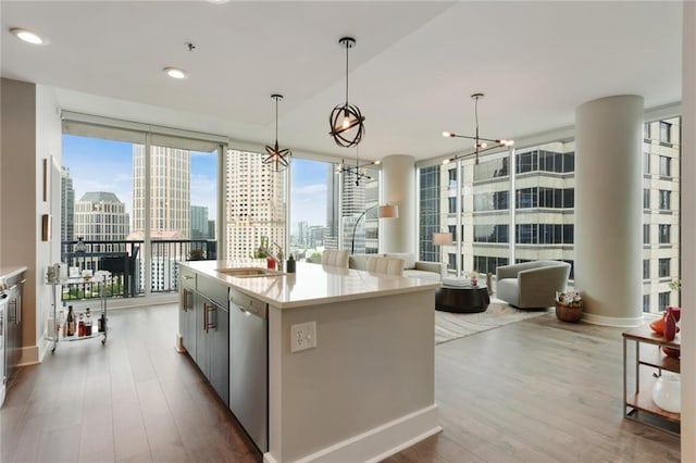 kitchen with dishwasher, sink, expansive windows, pendant lighting, and a kitchen island with sink