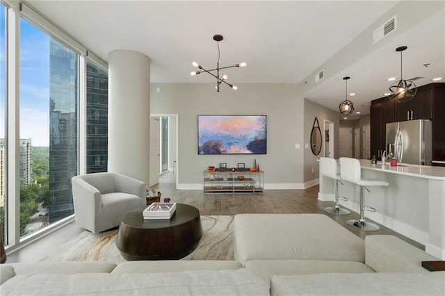 living room featuring a notable chandelier, plenty of natural light, wood-type flooring, and a wall of windows