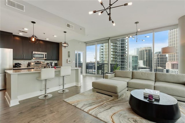 living room featuring floor to ceiling windows, hardwood / wood-style flooring, a healthy amount of sunlight, and a notable chandelier