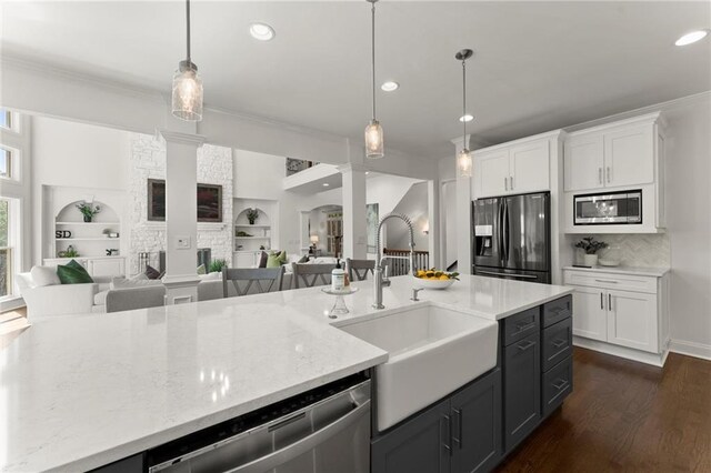 kitchen featuring stainless steel appliances, ornamental molding, a sink, and decorative columns