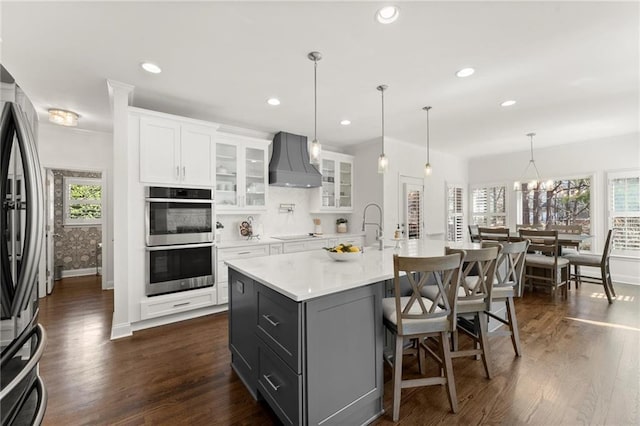 kitchen featuring stainless steel appliances, dark wood-style flooring, custom exhaust hood, and light countertops