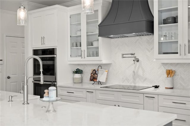 kitchen featuring white cabinetry, custom exhaust hood, tasteful backsplash, and decorative light fixtures