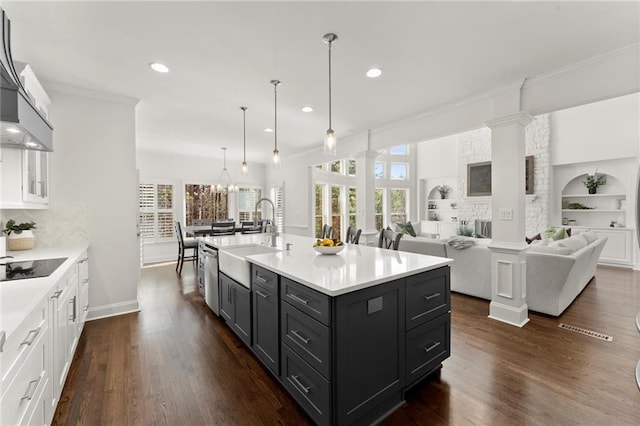 kitchen featuring dark wood-type flooring, light countertops, a sink, and ornate columns