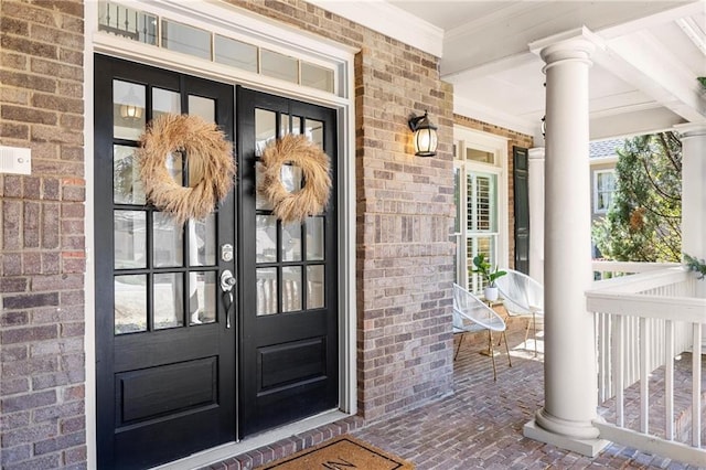 property entrance with brick siding, a porch, and french doors