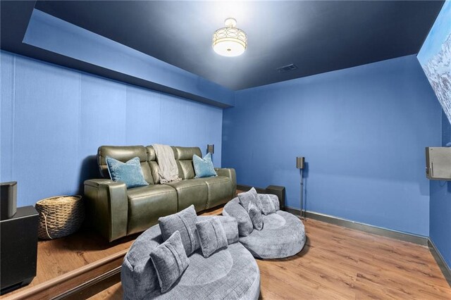 cinema room with wood finished floors, visible vents, and baseboards