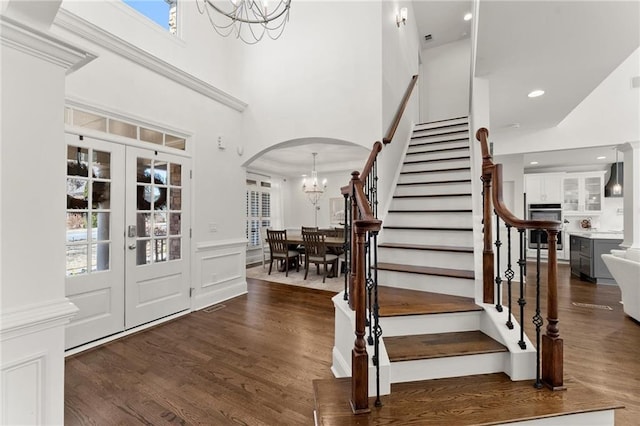 entryway featuring french doors, stairway, wood finished floors, and a notable chandelier