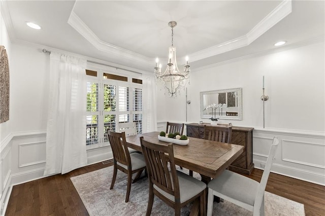 dining space featuring crown molding, a raised ceiling, a decorative wall, and wood finished floors