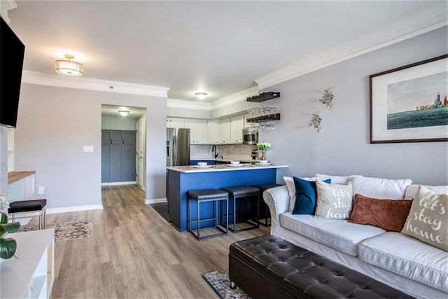 living room featuring light wood-type flooring, ornamental molding, and sink