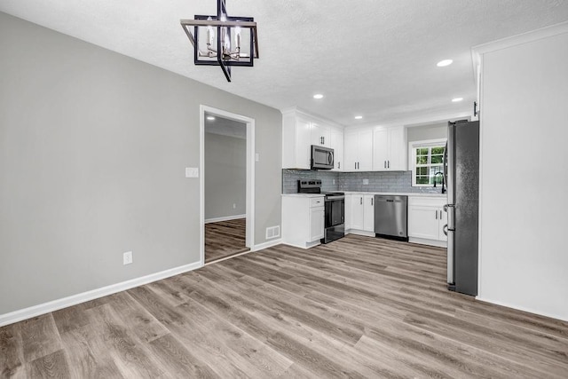 2089 Christian Cir SE, Conyers, GA 30013 - kitchen with appliances with stainless steel finishes, white cabinetry, light wood-style floors, tasteful backsplash, and recessed lighting