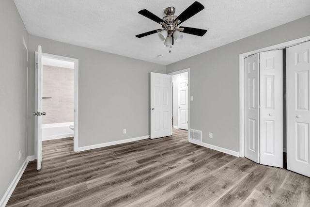 2089 Christian Cir SE, Conyers, GA 30013 - unfurnished bedroom featuring wood finished floors, a closet, ensuite bathroom, a textured ceiling, and ceiling fan