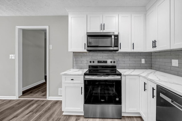 2089 Christian Cir SE, Conyers, GA 30013 - kitchen featuring appliances with stainless steel finishes, tasteful backsplash, light stone countertops, white cabinets, and a textured ceiling