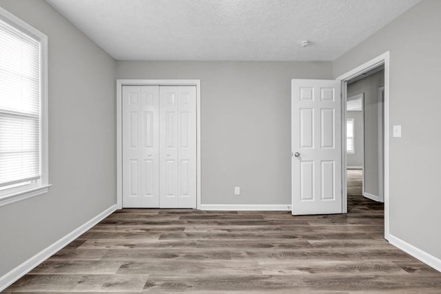 2089 Christian Cir SE, Conyers, GA 30013 - unfurnished bedroom featuring multiple windows, wood finished floors, a closet, and a textured ceiling