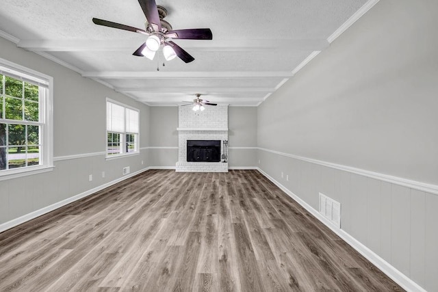 2089 Christian Cir SE, Conyers, GA 30013 - unfurnished living room with beamed ceiling, a textured ceiling, ceiling fan, wood finished floors, and a fireplace