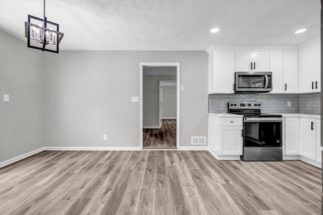2089 Christian Cir SE, Conyers, GA 30013 - kitchen featuring stainless steel appliances, a textured ceiling, light wood-style flooring, decorative backsplash, and white cabinets