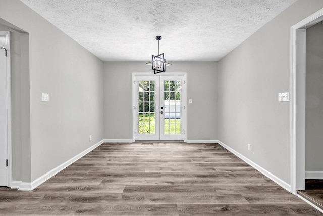2089 Christian Cir SE, Conyers, GA 30013 - unfurnished dining area featuring a textured ceiling, wood finished floors, a chandelier, and french doors