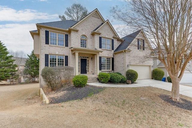 view of front of home with a garage, concrete driveway, brick siding, and roof with shingles