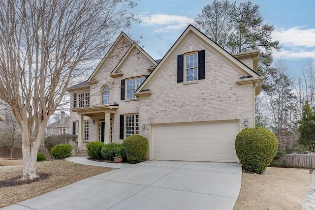 view of front of property featuring a garage, fence, concrete driveway, and brick siding