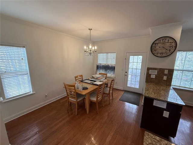 dining space with dark wood finished floors, a wealth of natural light, a chandelier, and ornamental molding