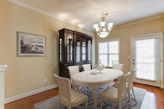 dining area with an inviting chandelier, ornamental molding, and hardwood / wood-style floors