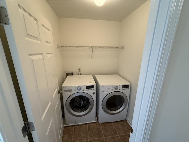 washroom with dark tile patterned floors, laundry area, and washing machine and dryer