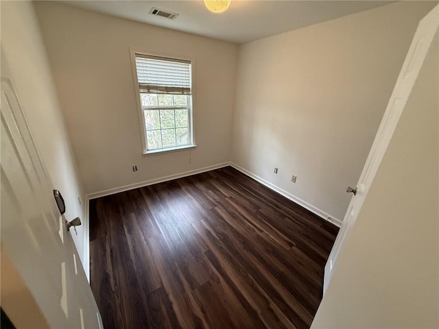 unfurnished room featuring dark wood-style floors, visible vents, and baseboards