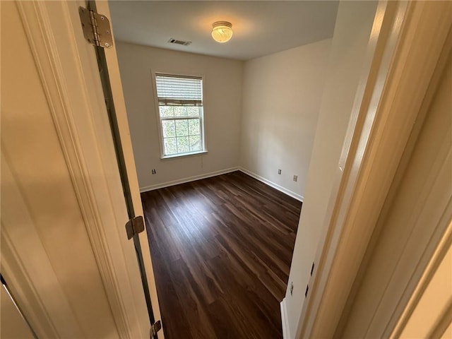 unfurnished room with dark wood finished floors, baseboards, and visible vents