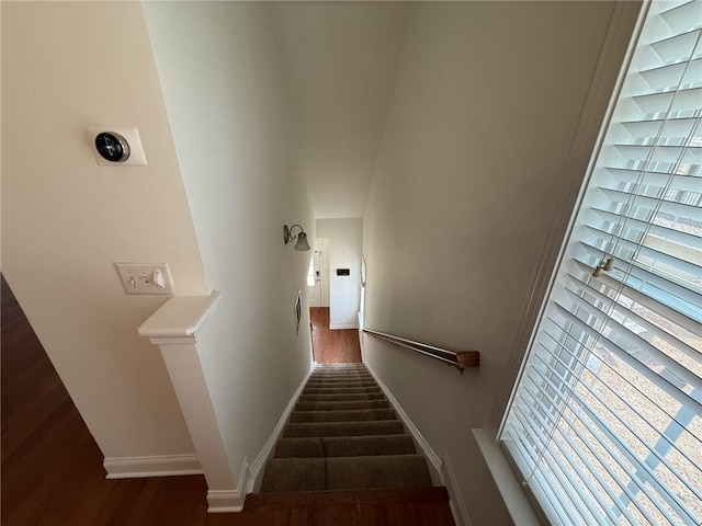 stairway with wood finished floors, baseboards, and a towering ceiling