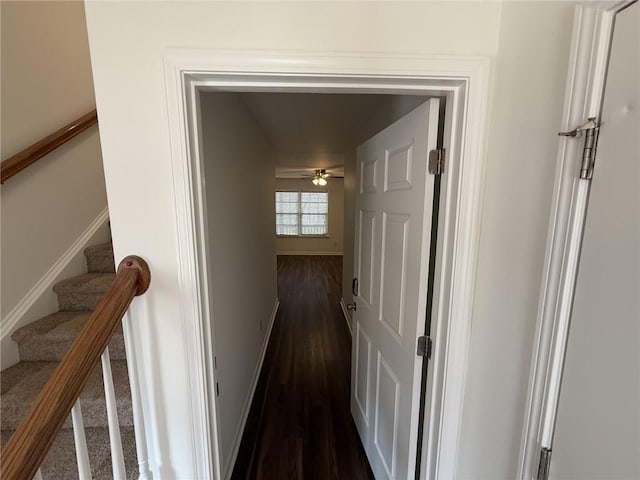 corridor with stairway, baseboards, and dark wood-style flooring