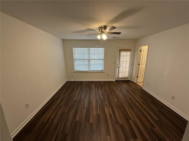 spare room with dark wood finished floors, a ceiling fan, and baseboards