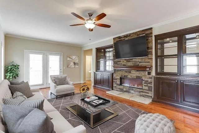 living room with crown molding, a stone fireplace, ceiling fan, and dark hardwood / wood-style flooring