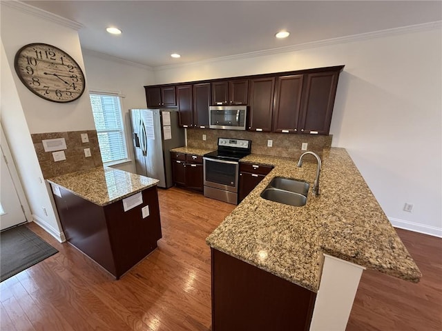 kitchen with a sink, stainless steel appliances, a peninsula, and dark wood-style flooring