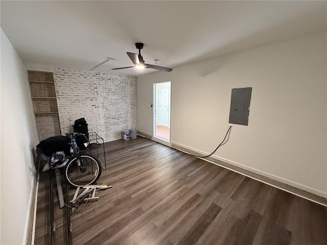 interior space with electric panel, dark wood finished floors, brick wall, and baseboards