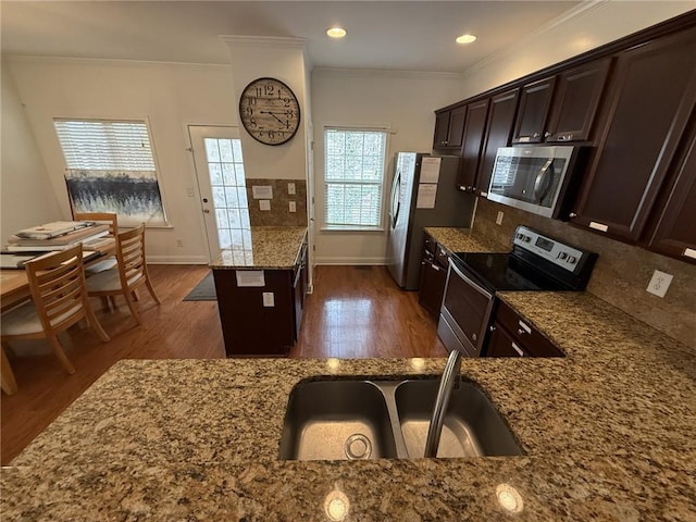 kitchen featuring backsplash, dark wood finished floors, ornamental molding, stone counters, and appliances with stainless steel finishes