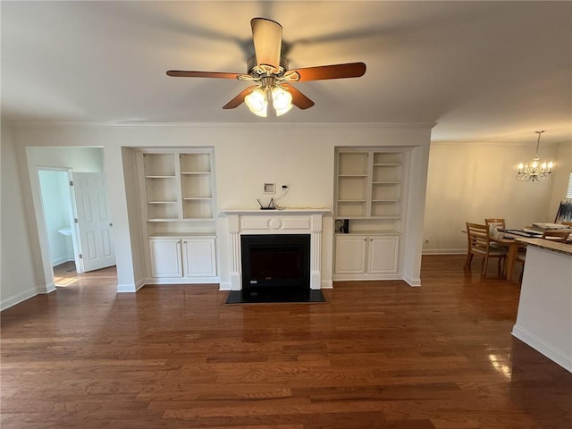 unfurnished living room featuring built in shelves, a fireplace with flush hearth, dark wood-type flooring, ornamental molding, and baseboards