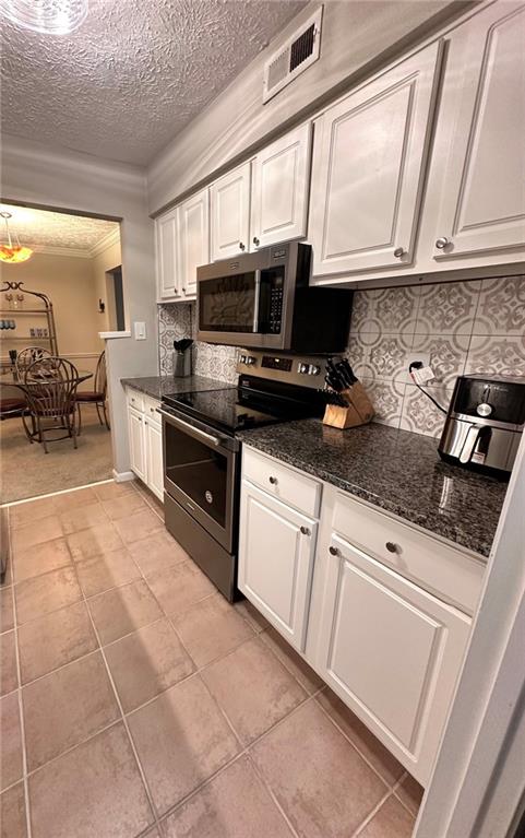 kitchen featuring white cabinets, light tile patterned flooring, backsplash, and appliances with stainless steel finishes