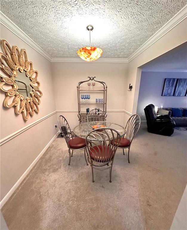 dining space featuring a textured ceiling, carpet floors, and crown molding