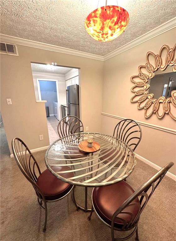 dining area featuring crown molding, carpet floors, and a textured ceiling