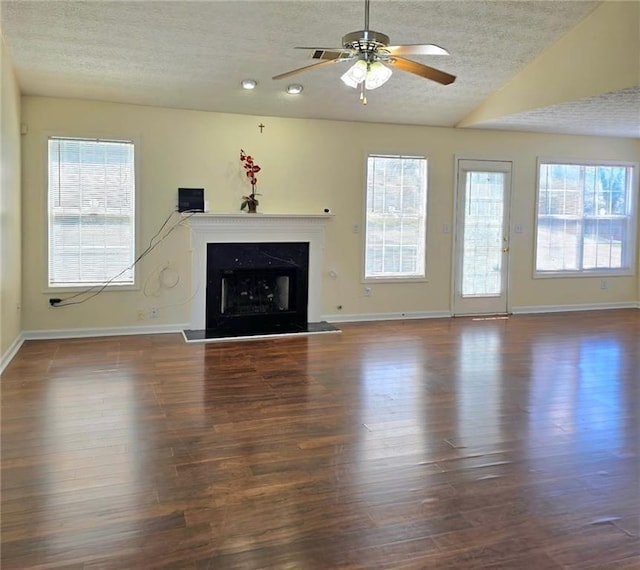 unfurnished living room featuring a premium fireplace, lofted ceiling, a textured ceiling, and wood finished floors