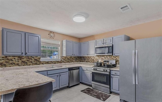 kitchen with sink, backsplash, light tile patterned floors, and stainless steel appliances