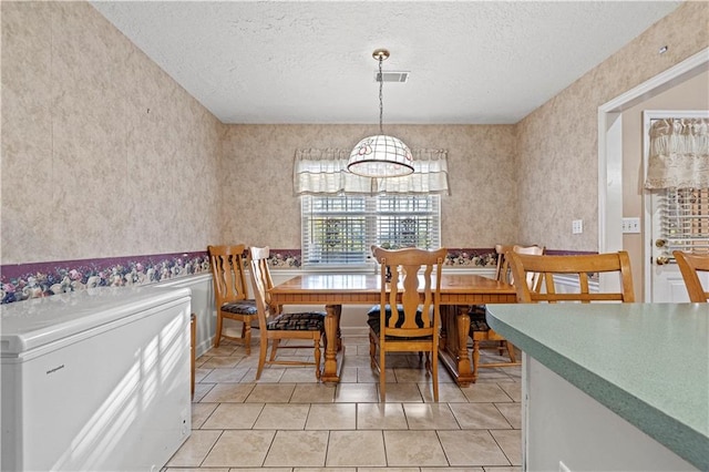 dining room with light tile patterned flooring, a textured ceiling, and a chandelier