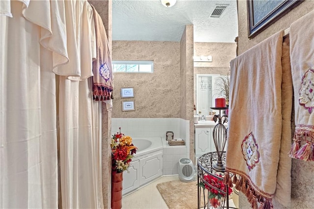 bathroom featuring a bath, a textured ceiling, and sink