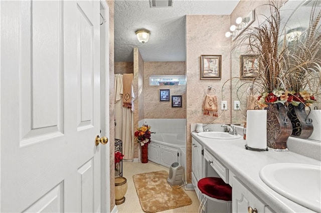 bathroom with a tub to relax in, vanity, and a textured ceiling