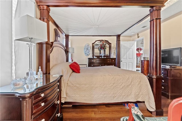 bedroom with dark hardwood / wood-style floors and decorative columns